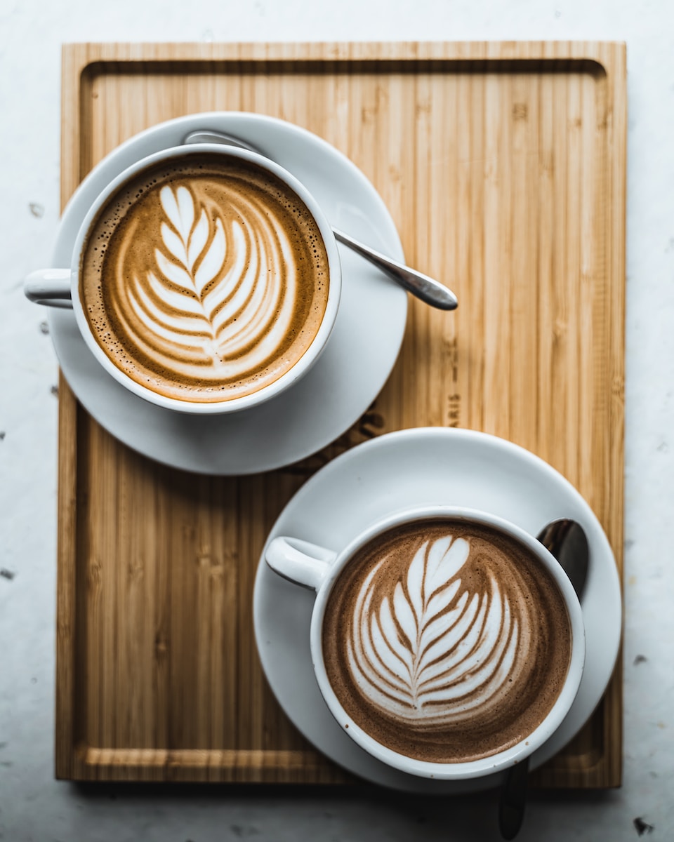 two cups of coffee on a wooden tray